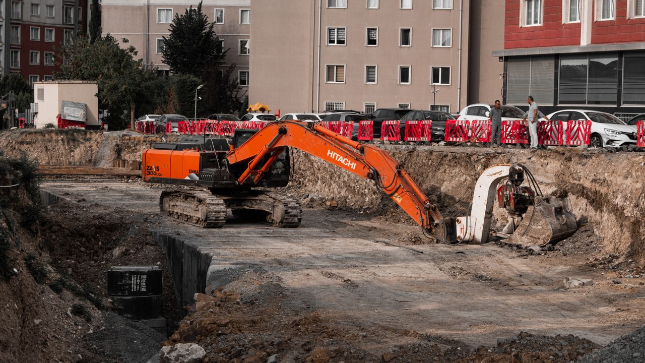 Excavators operating at an urban construction site, surrounded by residential buildings.